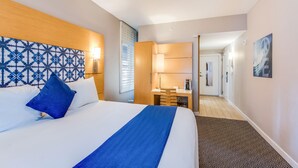 Una habitación de hotel con una cama, un escritorio y un baño a la vista.
