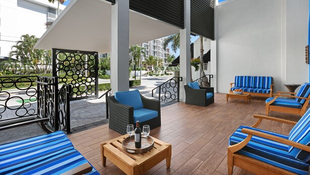 Un área lounge moderna al aire libre con asientos y una mesa dispuesta con copas y una botella.