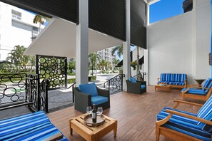 A modern outdoor lounge area with seating and a table set with glasses and a bottle. - The Landon Bay Harbor - Miami Beach (Bay Harbor Islands)