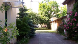 A narrow concrete pathway flanked by lush greenery and a building with a sloped roof. - Hotel Pension Streuhof Berlin (Berlin)