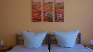 A room with two beds, each with a single pillow, and a wall with three paintings. - Hotel Pension Streuhof Berlin (Berlin)