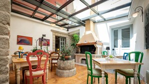 A cozy dining area with wooden flooring, a stone table, and chairs with green and red upholstery. - Hotel Kastel (Motovun)
