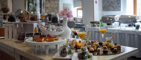 Una mesa de buffet con diferentes alimentos, entre ellos pasteles, postres y bebidas.