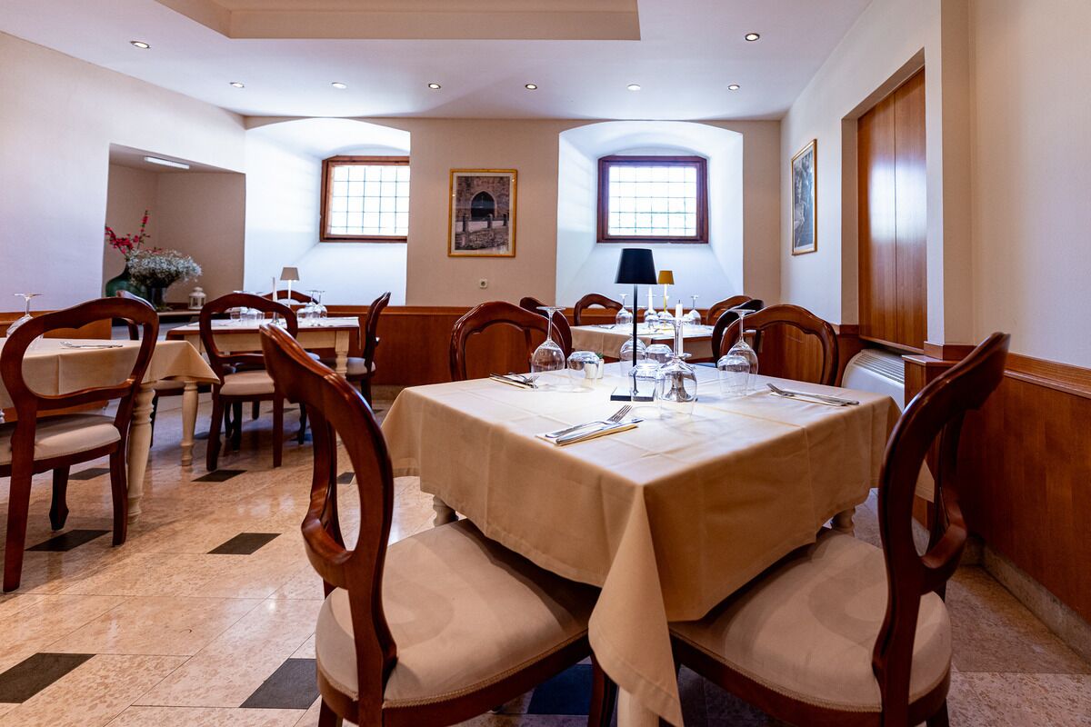 A dining area with multiple tables, chairs, and a chandelier.