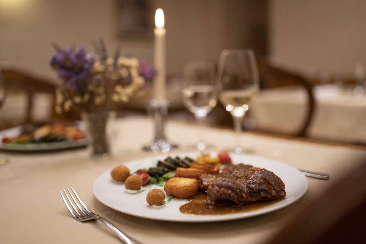 A dining table with a plate of food, a candle, and a wine glass.