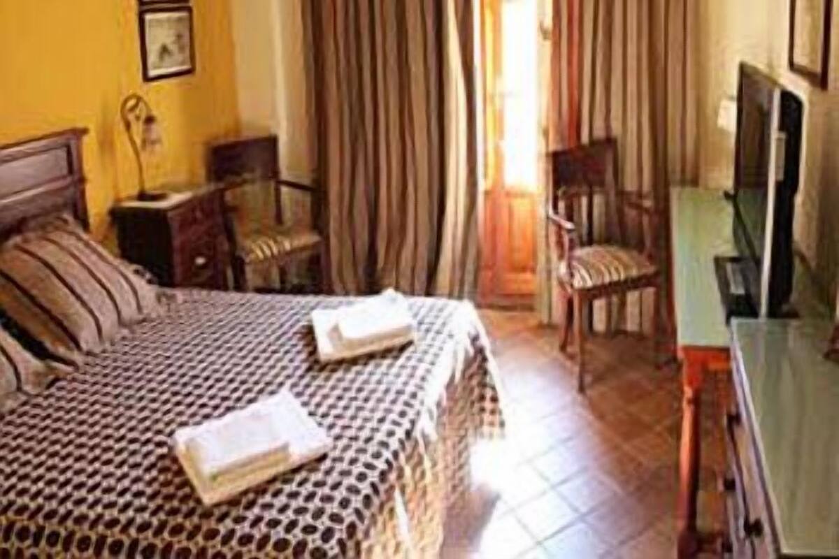 A hotel room with a bed, a chair, a desk, and a television.