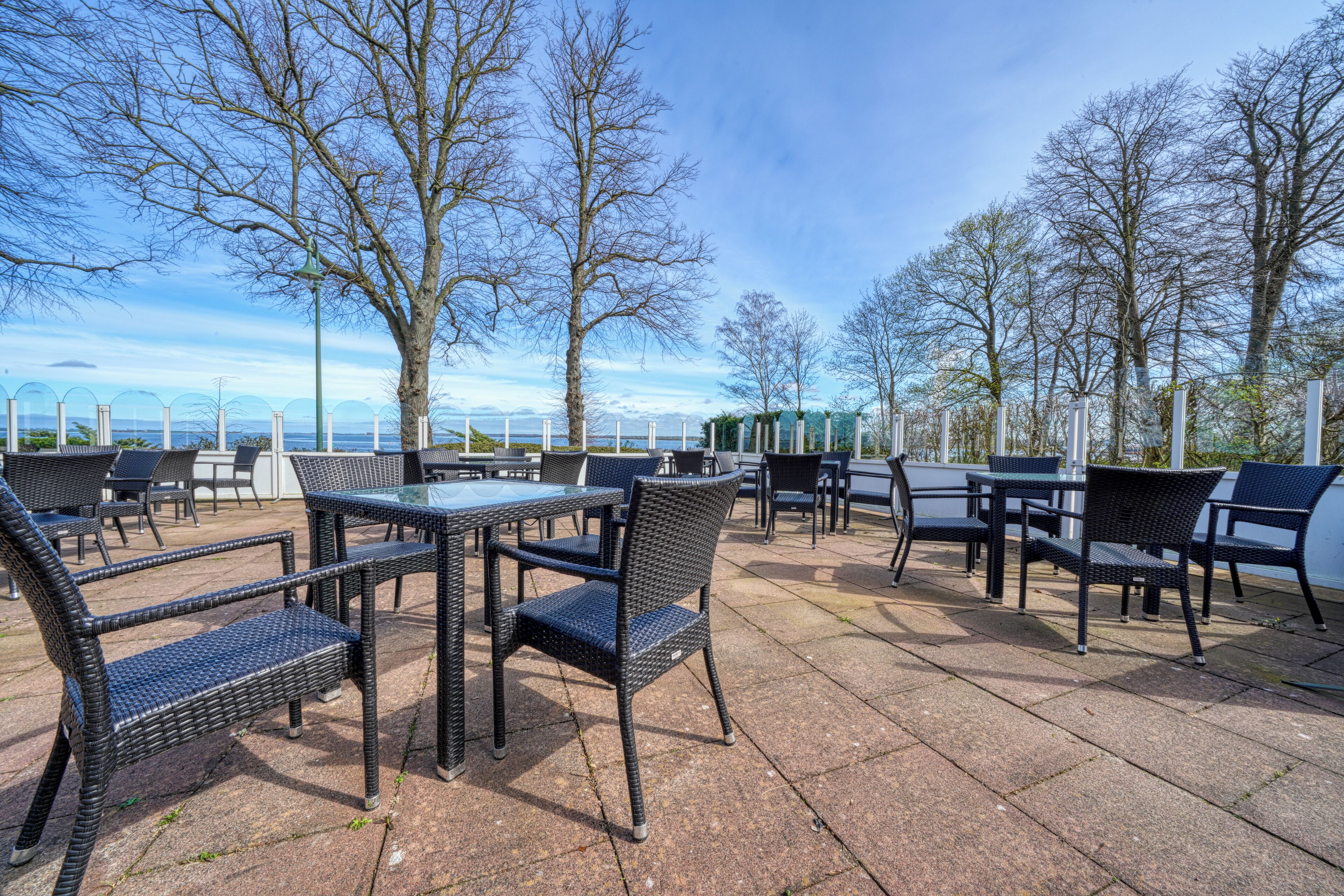 An outdoor patio area with wicker furniture and a view of the sea.