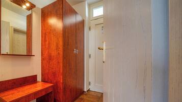 A bathroom with a wooden vanity, a large mirror, and a door leading to another room.