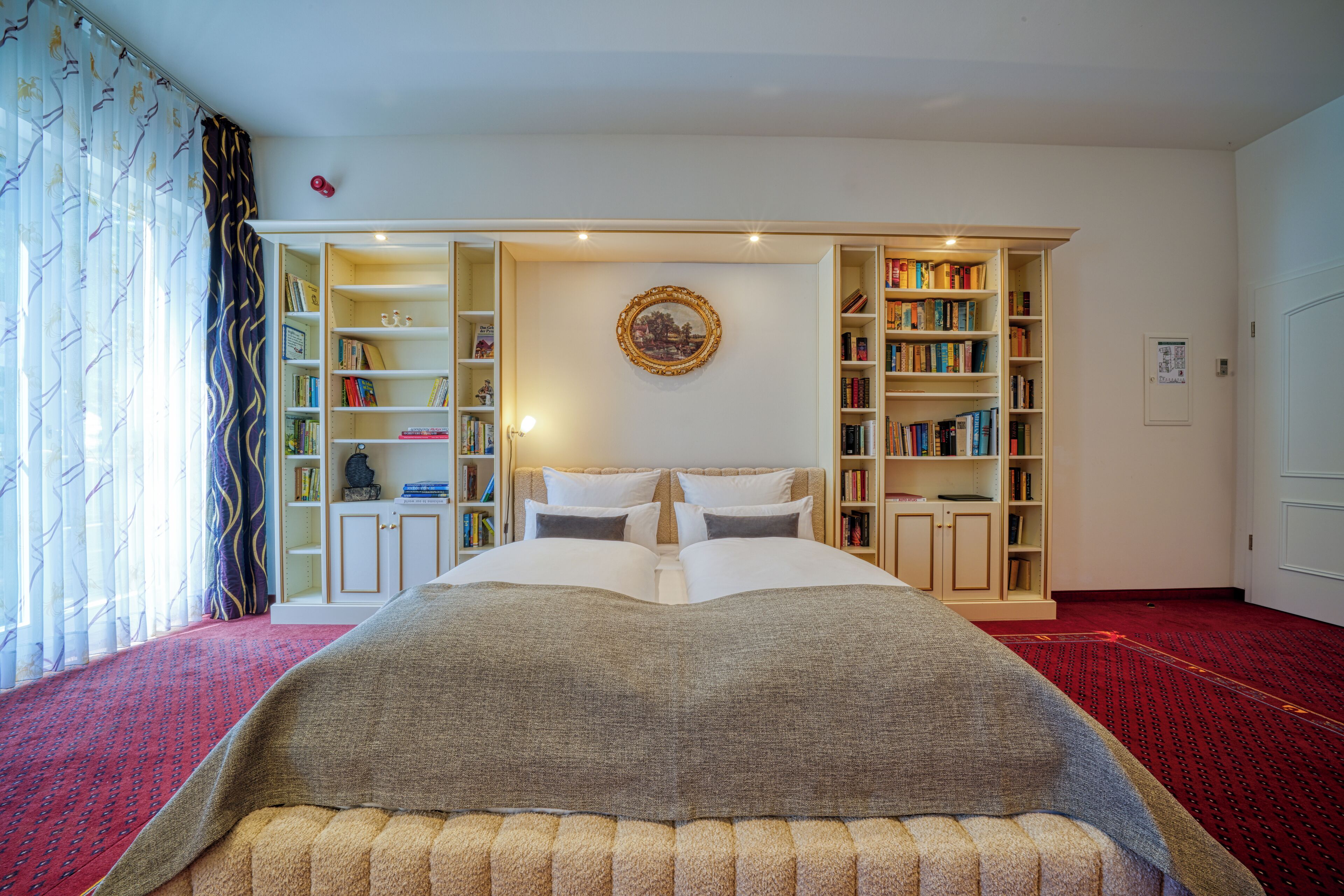 Un dormitorio con una cama grande, una estantería y piso alfombrado.