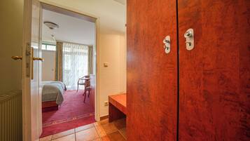 A hotel room with a bed, a wooden wardrobe, and a small desk.