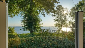 A view from a window overlooking a body of water, a bridge, and a large tree. - Hotel Seeblick Wismar (Wismar)
