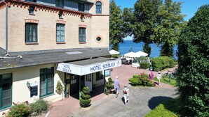 A hotel with a tower, a covered entrance, and a view of the sea. - Hotel Seeblick Wismar (Wismar)