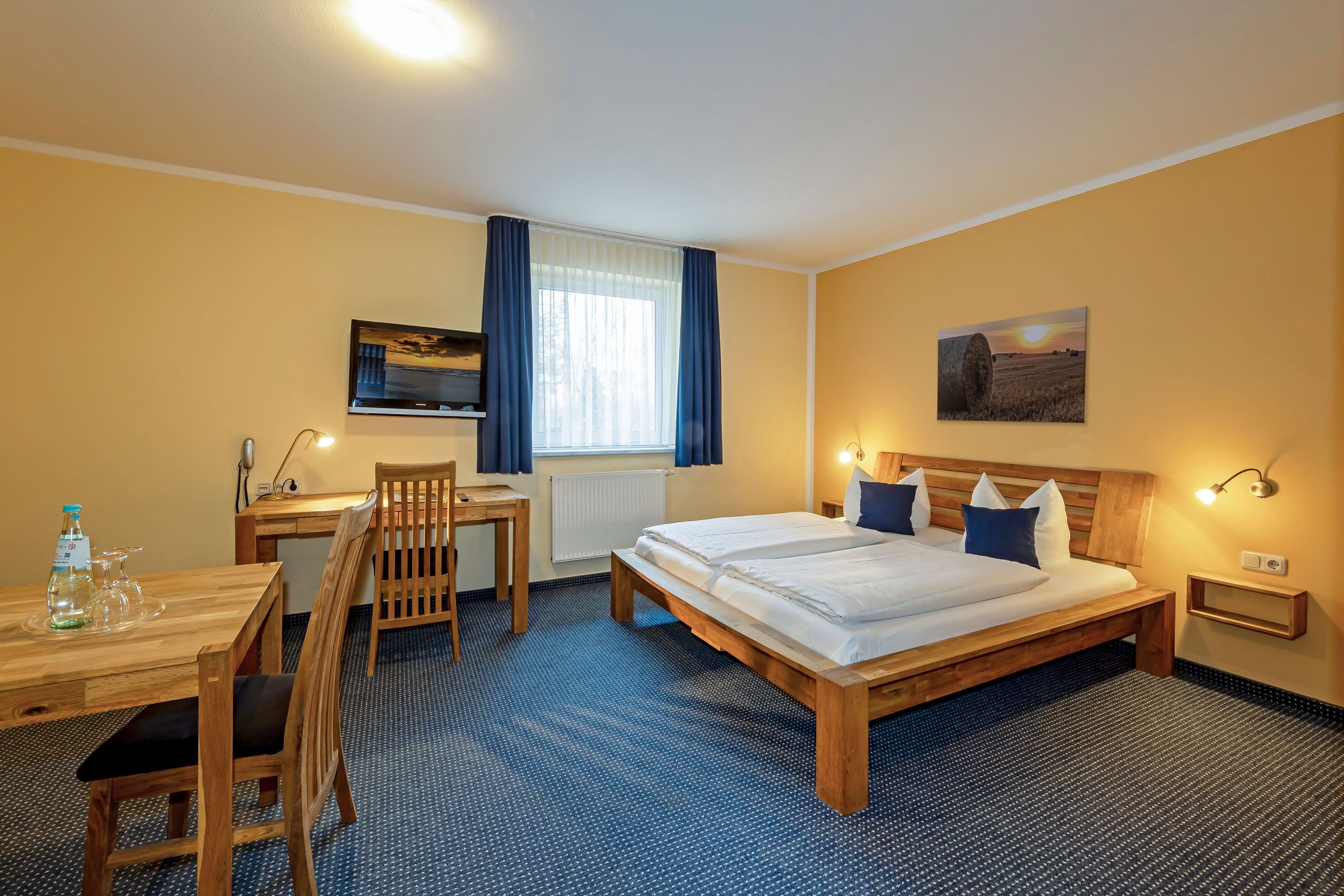 Ein Hotelzimmer mit Bett, Schreibtisch, Stuhl und Fernseher.
