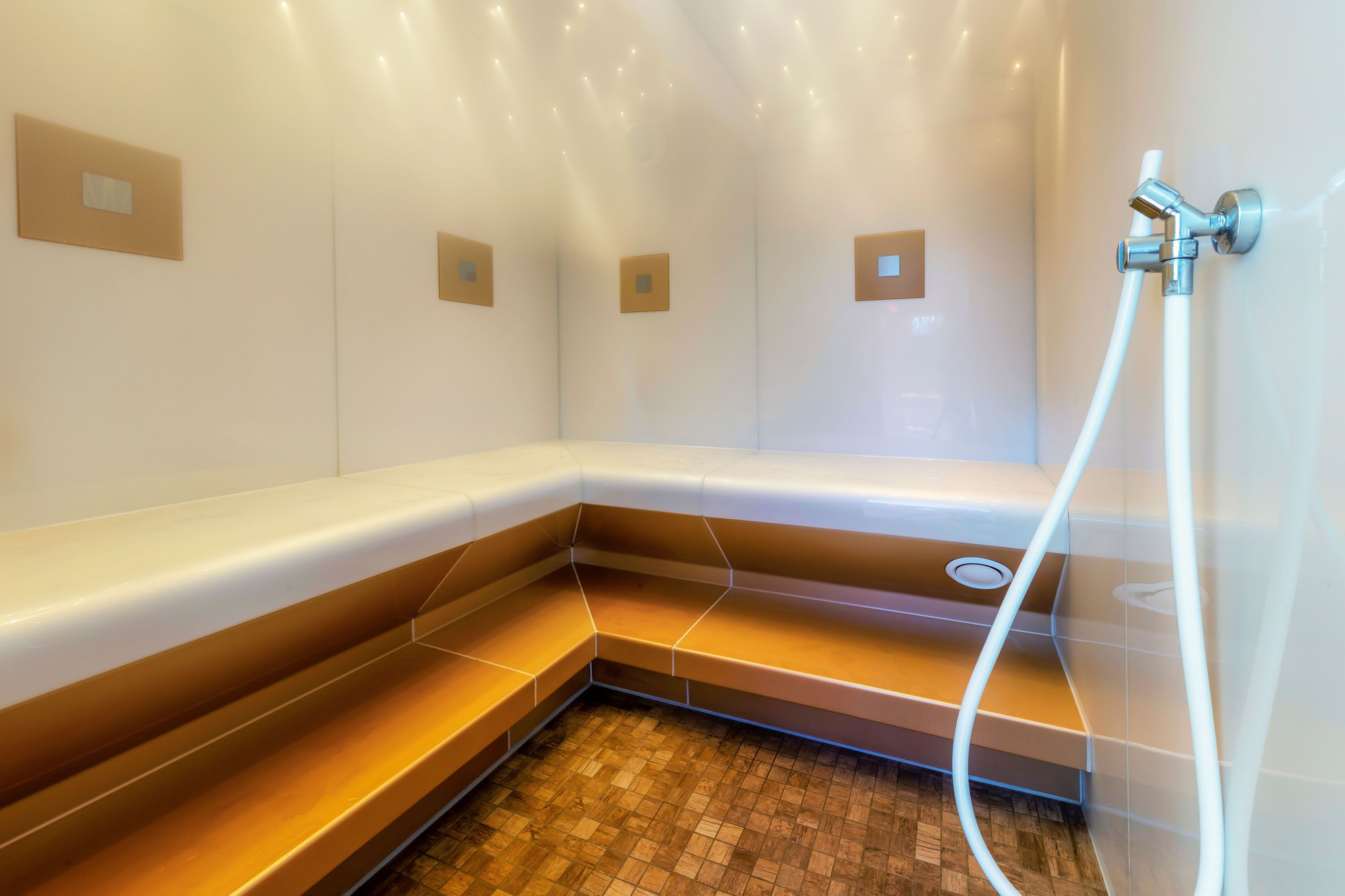 Ein modernes Duschbad mit Sitzbank, Wandarmatur und Fliesenboden.