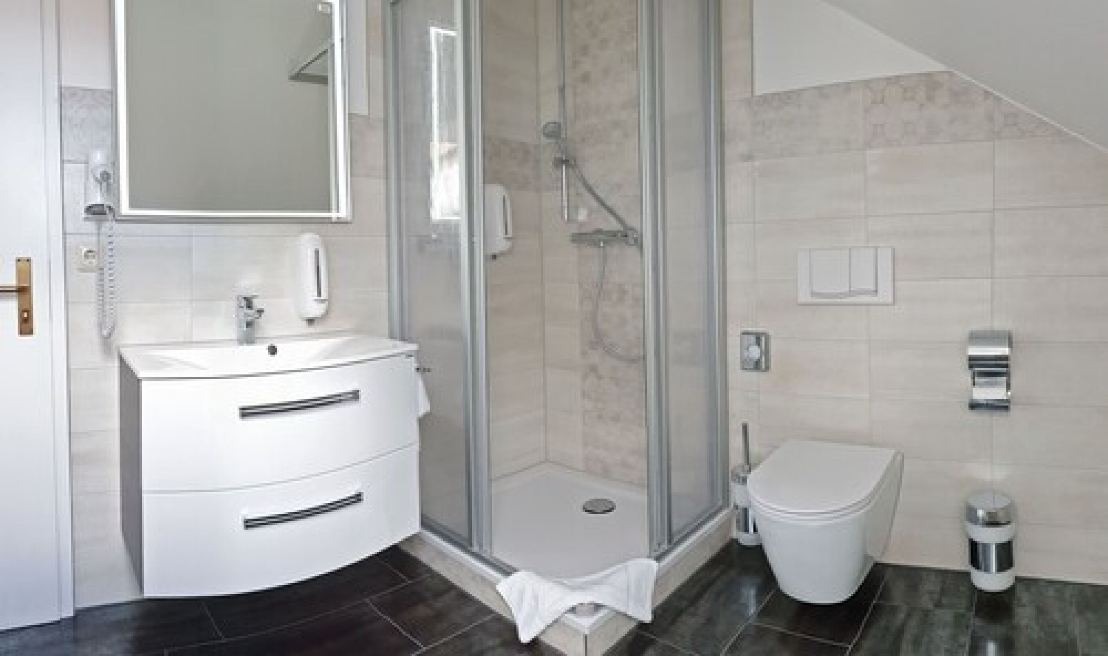 Ein modernes Badezimmer mit einer Duschkabine, einem weißen Waschbecken und einer Toilette.