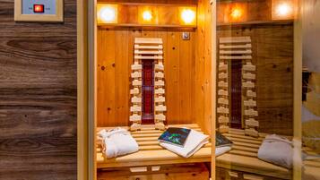 A sauna room with wooden benches, a control panel, and a mirror.
