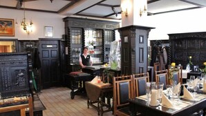 A traditional dining area with wooden furniture, a bar area with a bartender, and a tiled floor. - Hotel und ReuterHaus (Wismar)