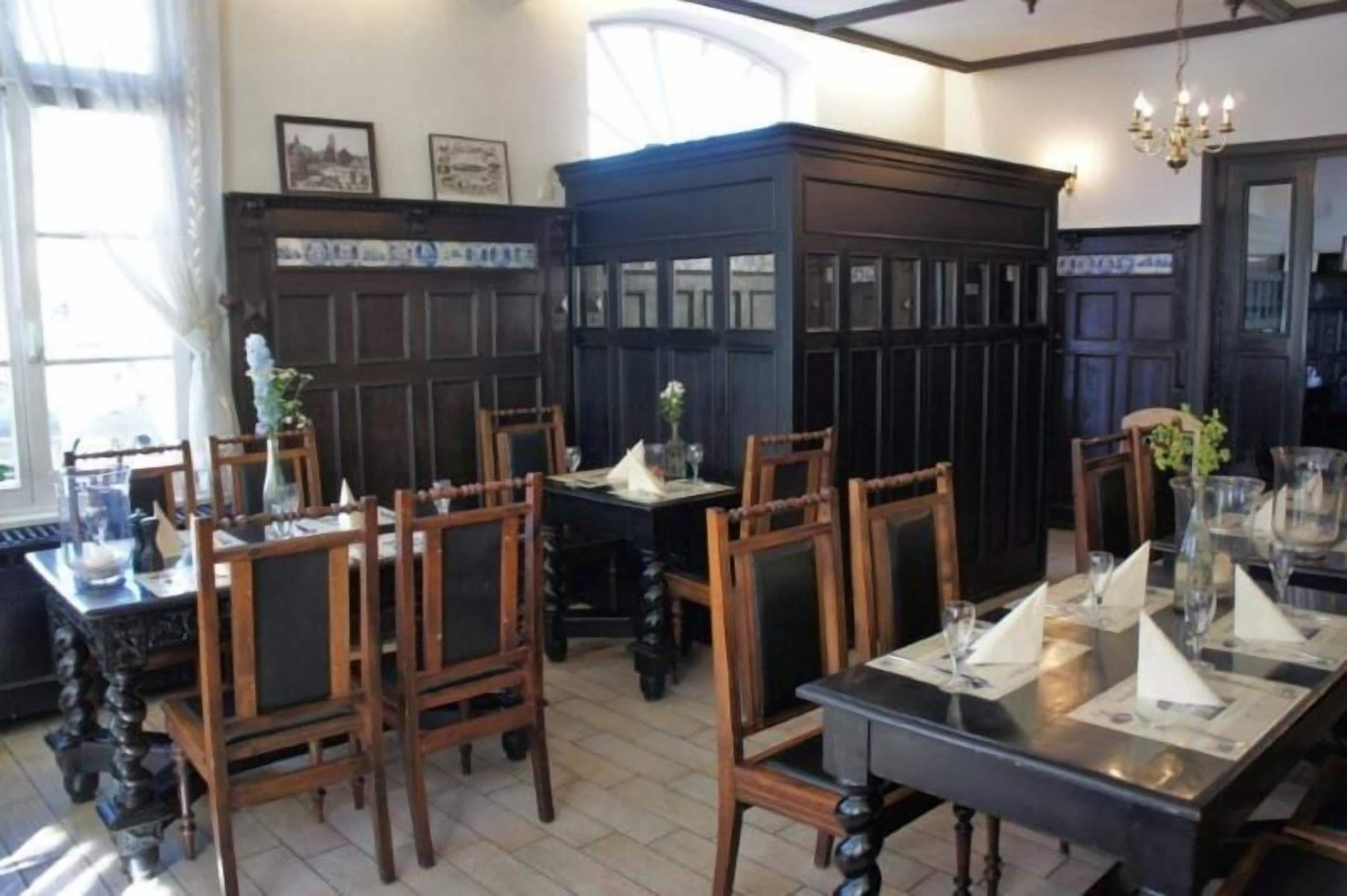 A dining area with wooden chairs and tables, a dark wooden cabinet, and a chandelier.