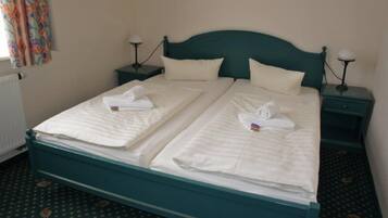 A double bed with two nightstands, each with a lamp, in a room with patterned carpet.
