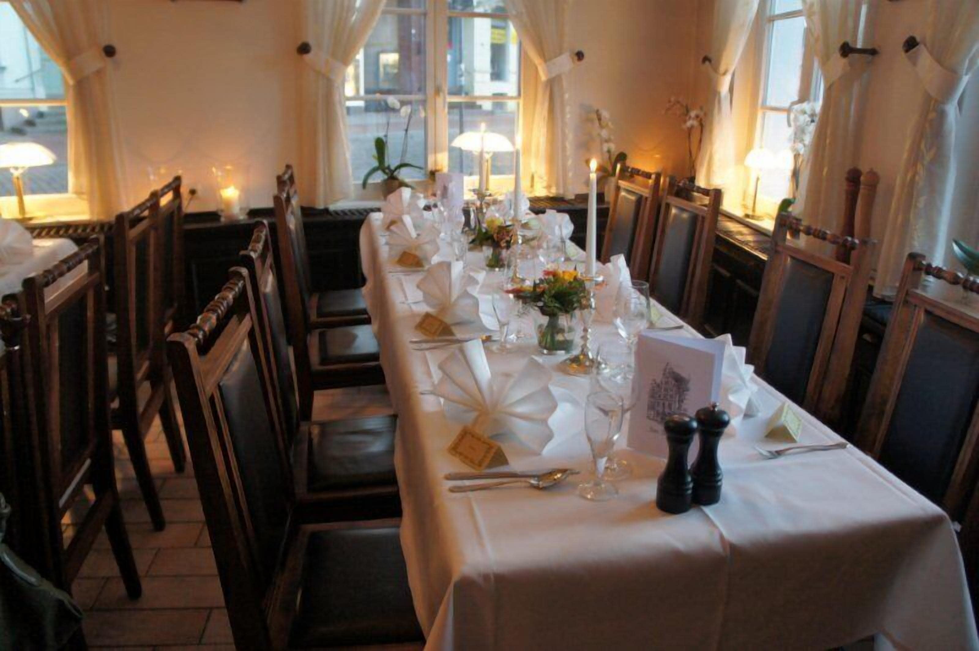 A long dining table set with white tablecloths, candles, and floral centerpieces.