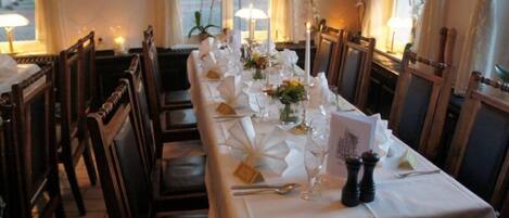 A long dining table set with white tablecloths, candles, and floral centerpieces.