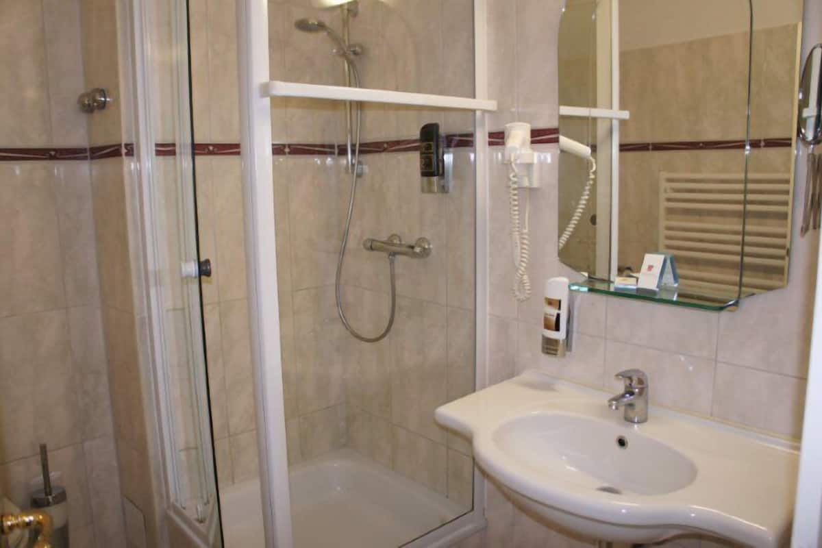 Ein Badezimmer mit einer gläsernen Dusche, einem weißen Waschbecken und einem Spiegel darüber.