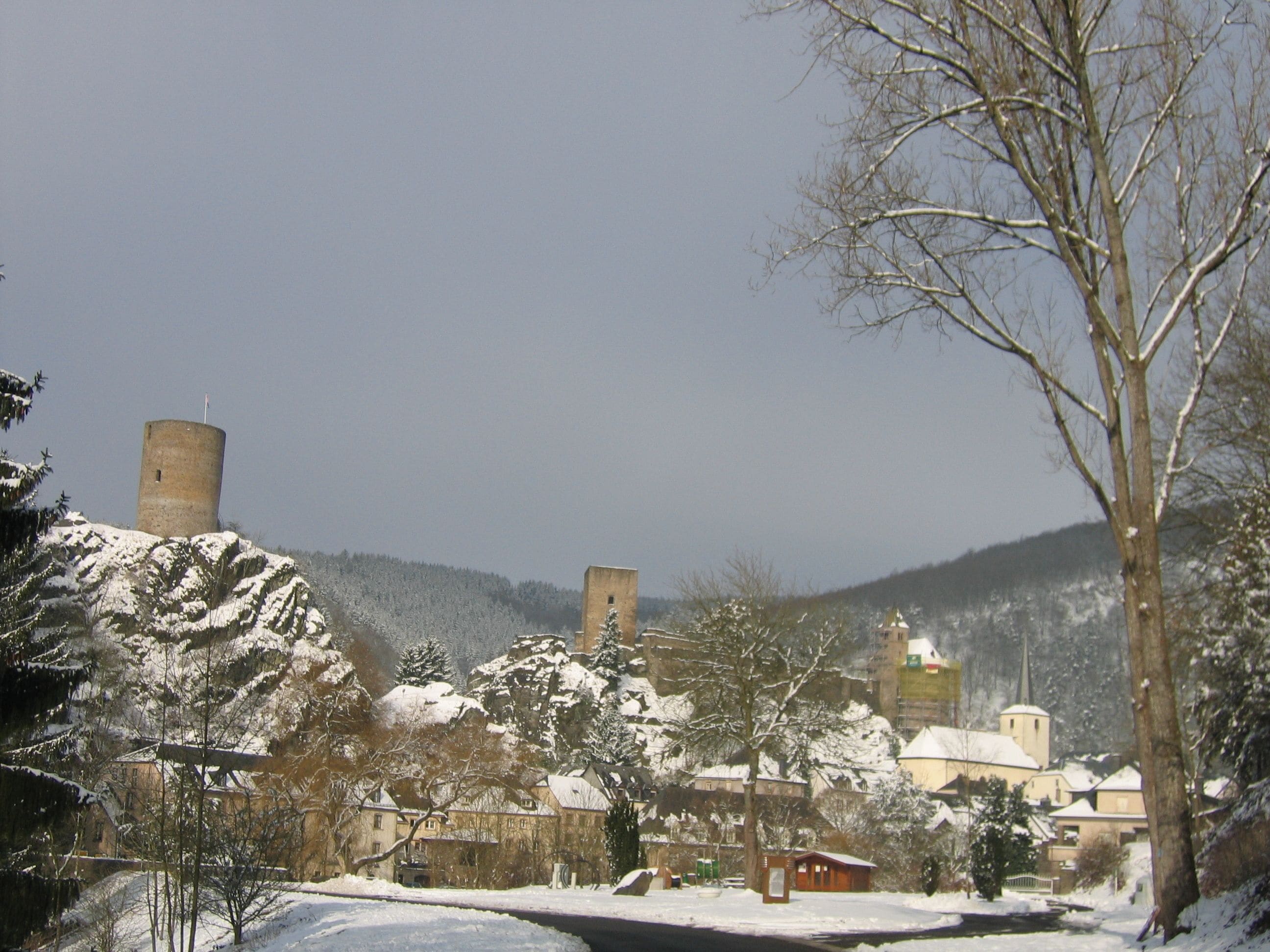 Une ville historique dotée de tours médiévales, de bâtiments enneigés et d’une église avec un clocher.