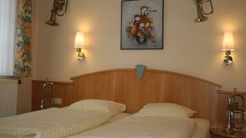 A hotel room with two beds, a wooden headboard, wall-mounted lamps, and a painting above the beds.