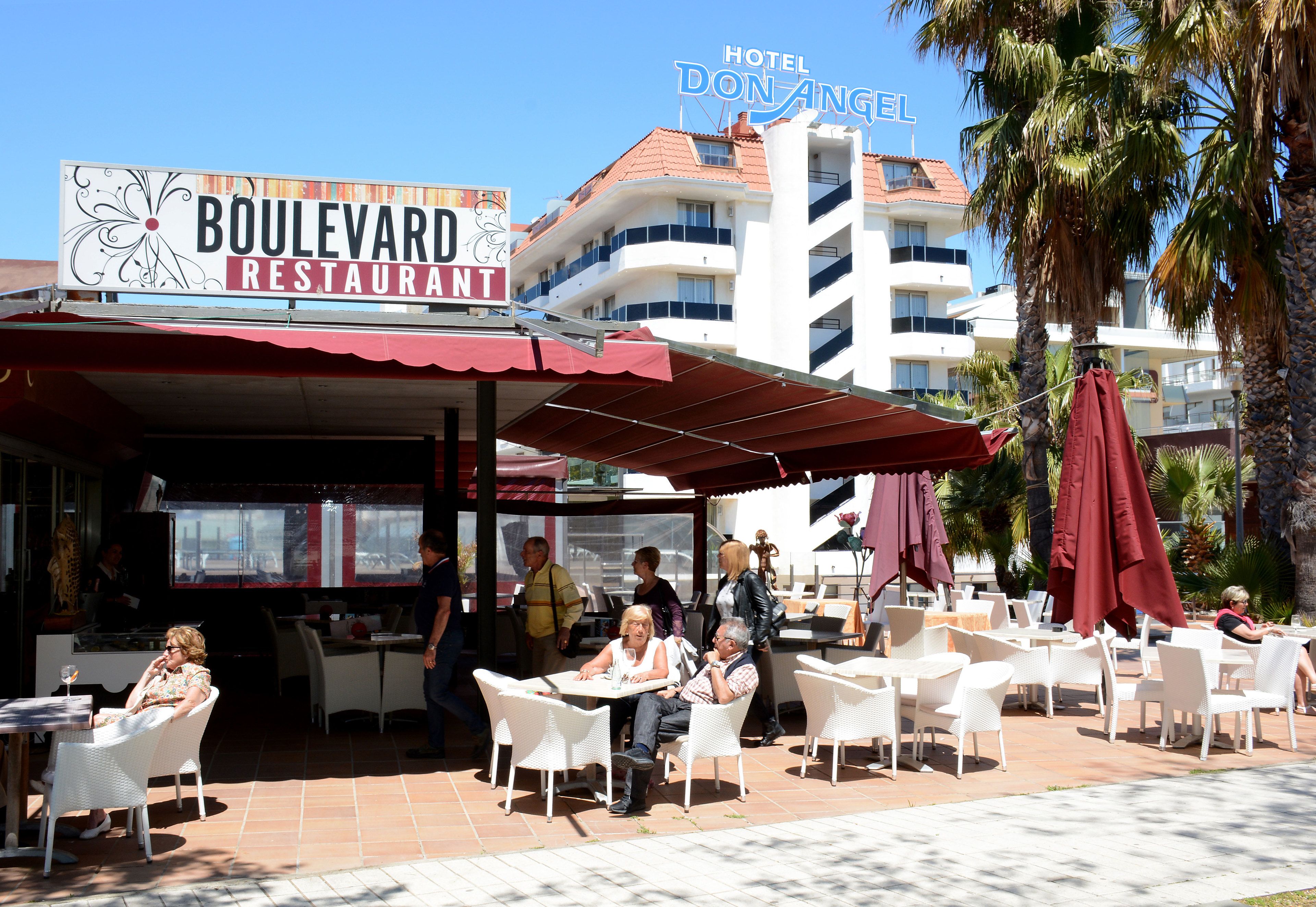 Un restaurant avec une terrasse, une enseigne indiquant « Restaurant Boulevard », et un bâtiment portant l’inscription « Hôtel Don Angel ».