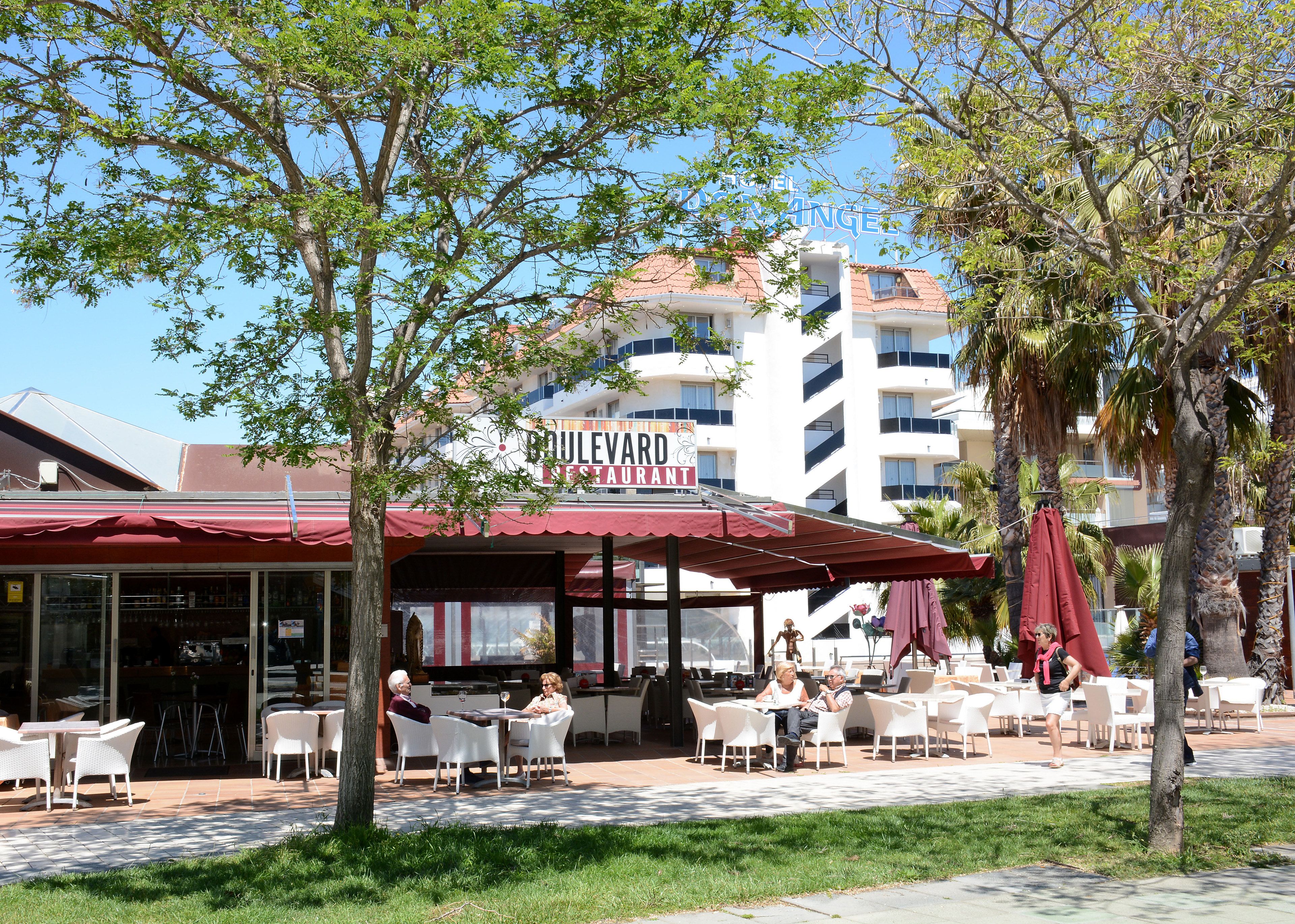 An outdoor seating area with tables and chairs, a red awning, and a sign for Boulevard Restaurant.