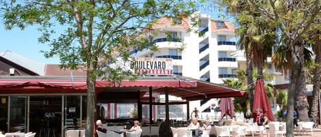 An outdoor seating area with tables and chairs, a red awning, and a sign for Boulevard Restaurant.