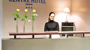 A reception desk at the Centre Hotel with a modern design, featuring a reception area, a lamp, and three vases with yellow flowers. - Centre Hotel (Kaunas)