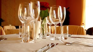 A table set for dining with multiple wine glasses, a vase with a red rose, and a small glass of water. - Centre Hotel (Kaunas)