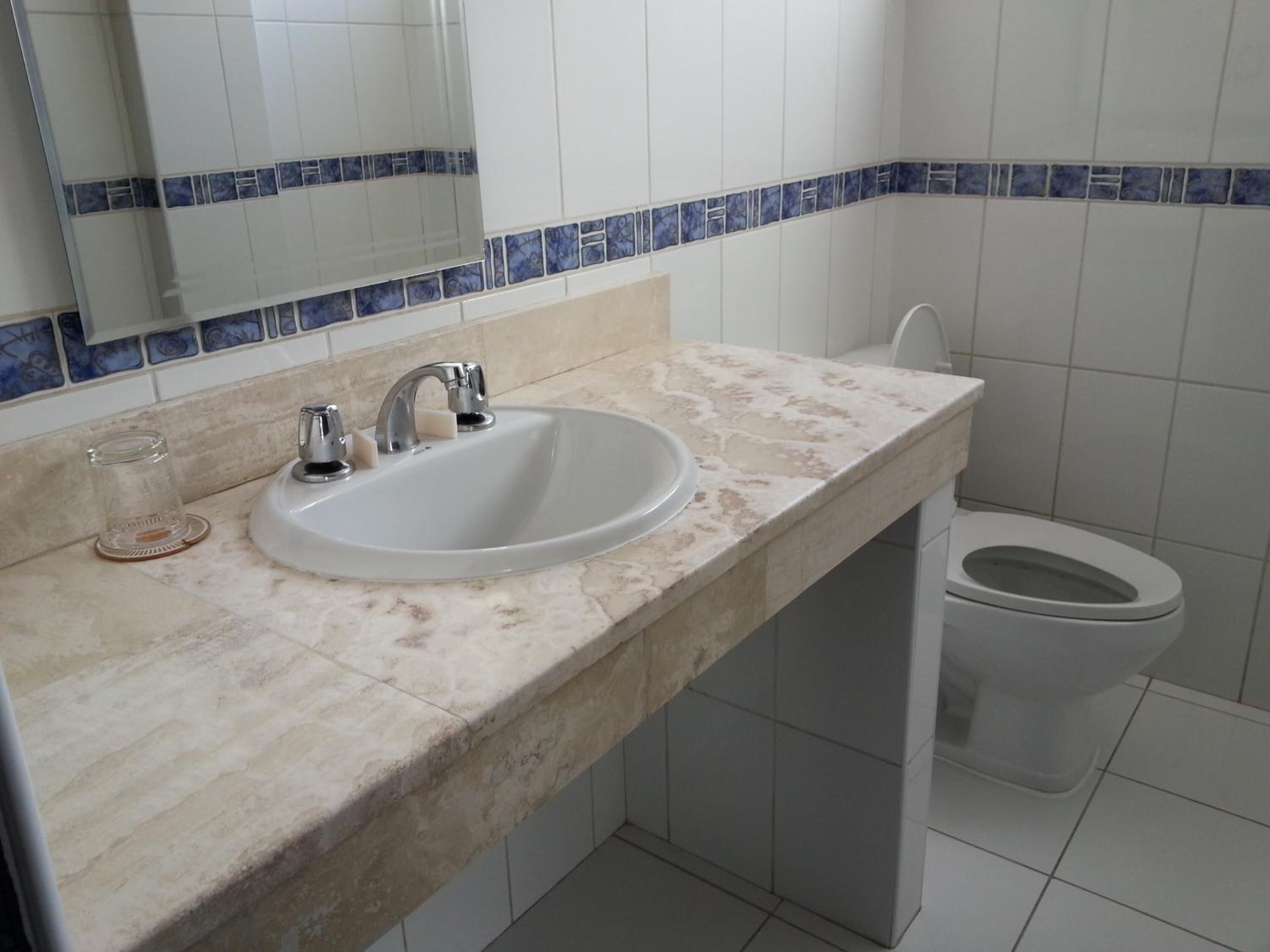 A bathroom with a white sink, a mirror above it, and a toilet.