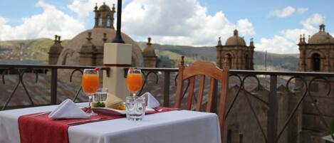 A table set for breakfast with a view of historic buildings and a clear sky.