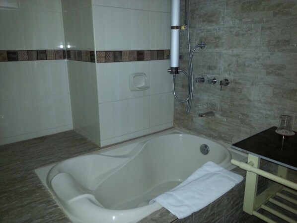 Un baño con una bañera independiente, un perchero y un cabezal de ducha.