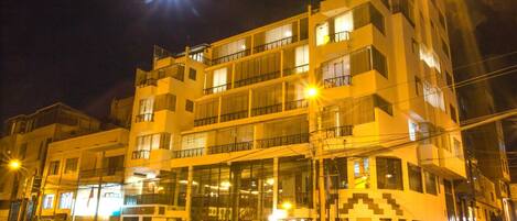 Un hotel de varios pisos con fachada de vidrio, balcones y entrada a nivel de calle.