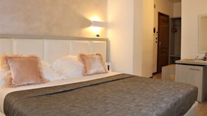 Una habitación de hotel con cama, mesita de noche, espejo y puerta que da a un baño.