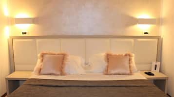 Une chambre d’hôtel avec un grand lit, deux tables de chevet et des lampes fixées au mur.