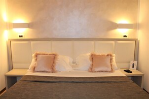 Habitación de hotel con una cama grande, dos mesitas de noche y lámparas de pared.