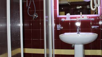 A bathroom with a glass-enclosed shower, a sink, and a mirror with a ring light.
