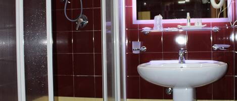 A bathroom with a glass-enclosed shower, a sink, and a mirror with a ring light.