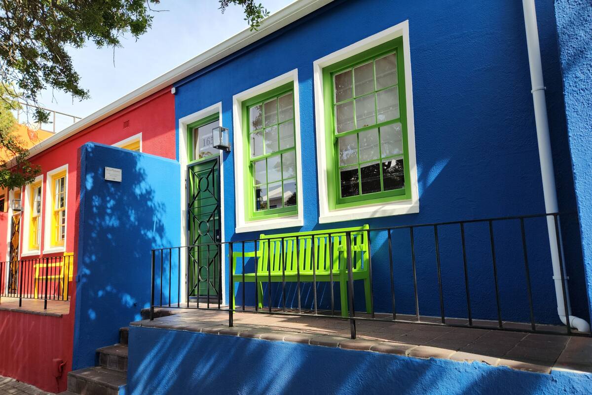 A building with a blue facade, green windows, and a red door.