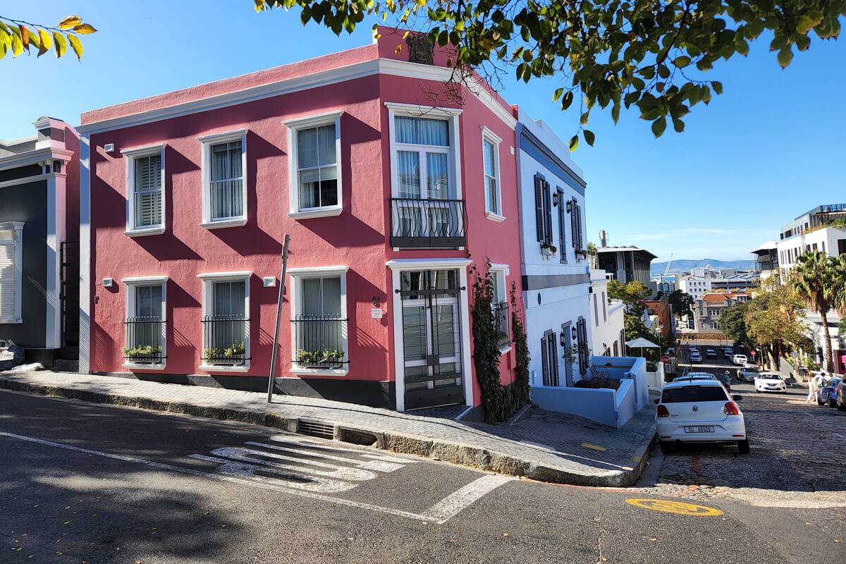 A two-story building with a red facade and white trim, featuring multiple windows and a balcony.