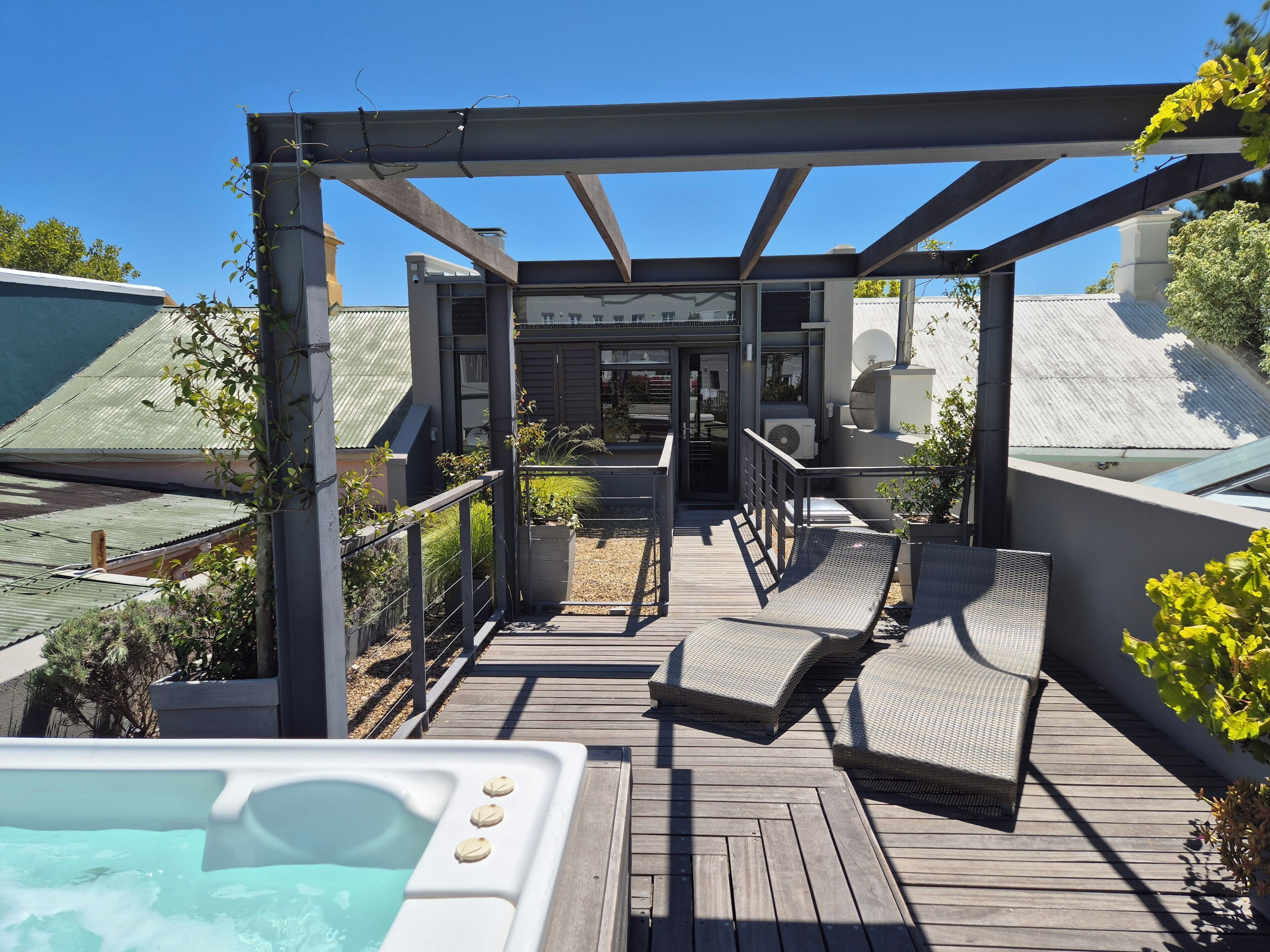 Une terrasse sur le toit équipée d’un jacuzzi, de chaises longues et offrant une vue sur l’intérieur du bâtiment.