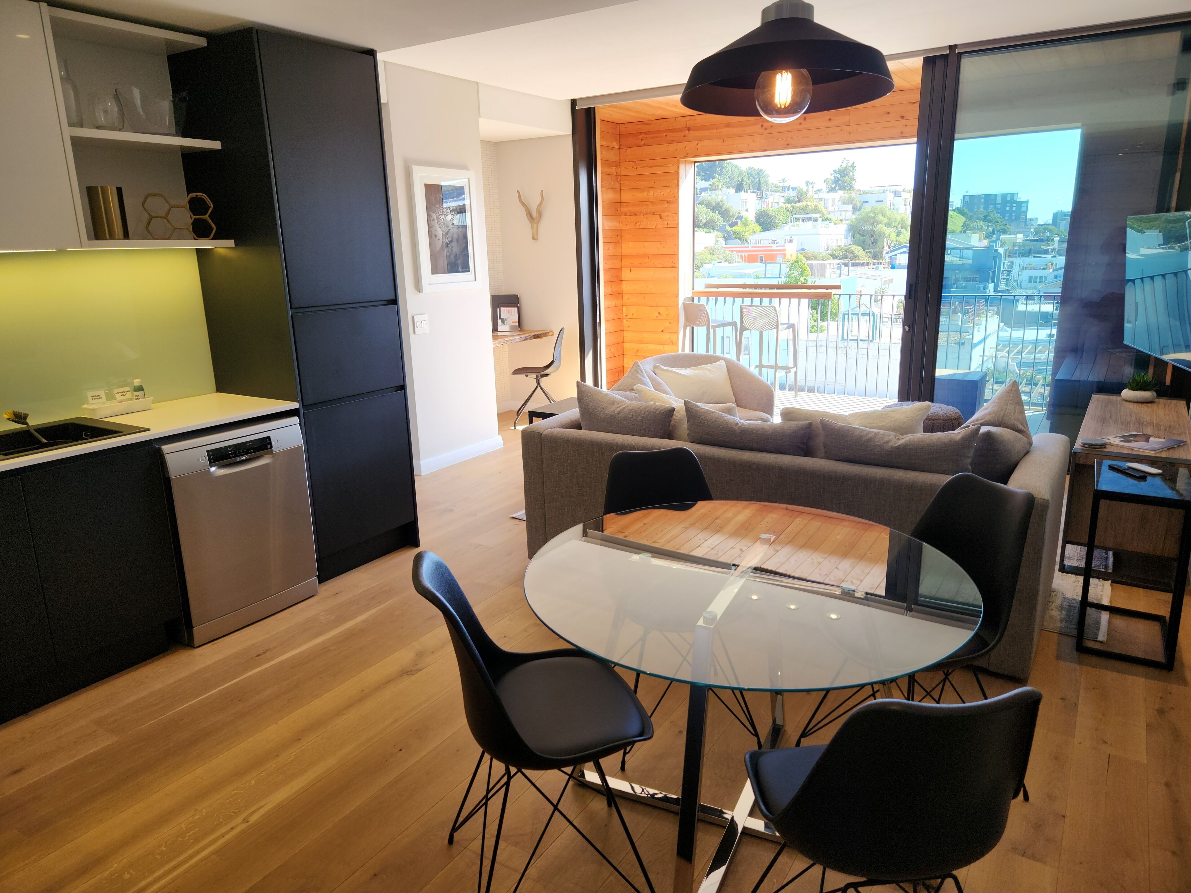 A modern apartment with a kitchen, dining area, and a balcony with a city view.