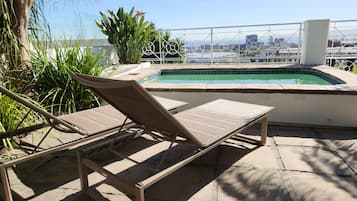 Relax by the pool surrounded by lush greenery and a city view.