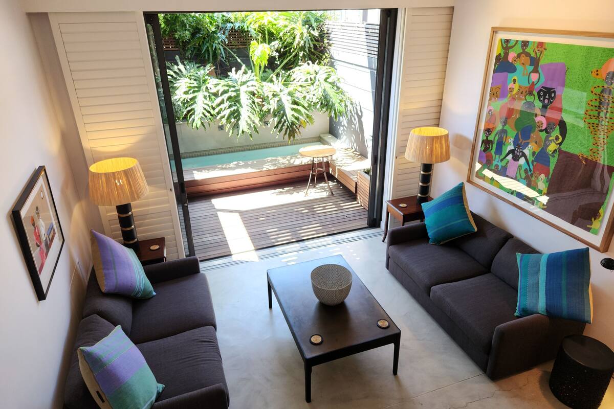 A modern living room with a sofa set, a coffee table, and a painting on the wall.