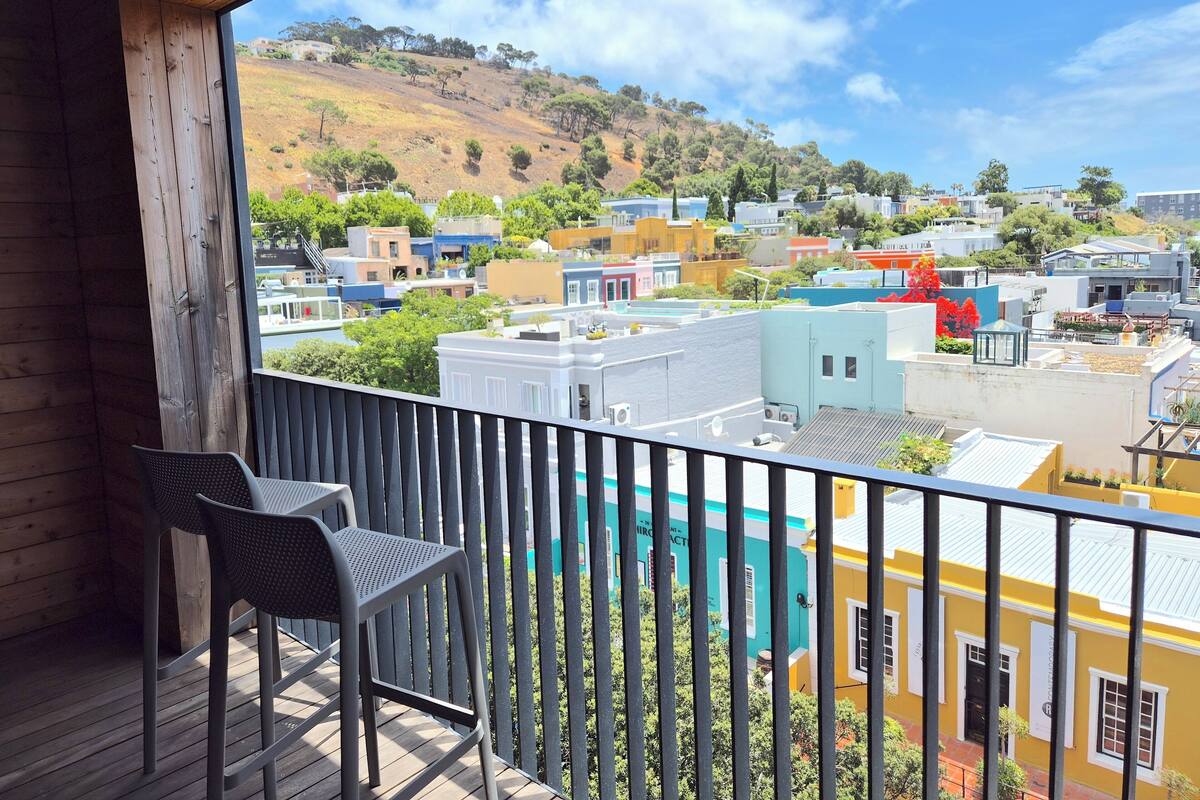 A balcony with a view of colorful buildings and a hillside.