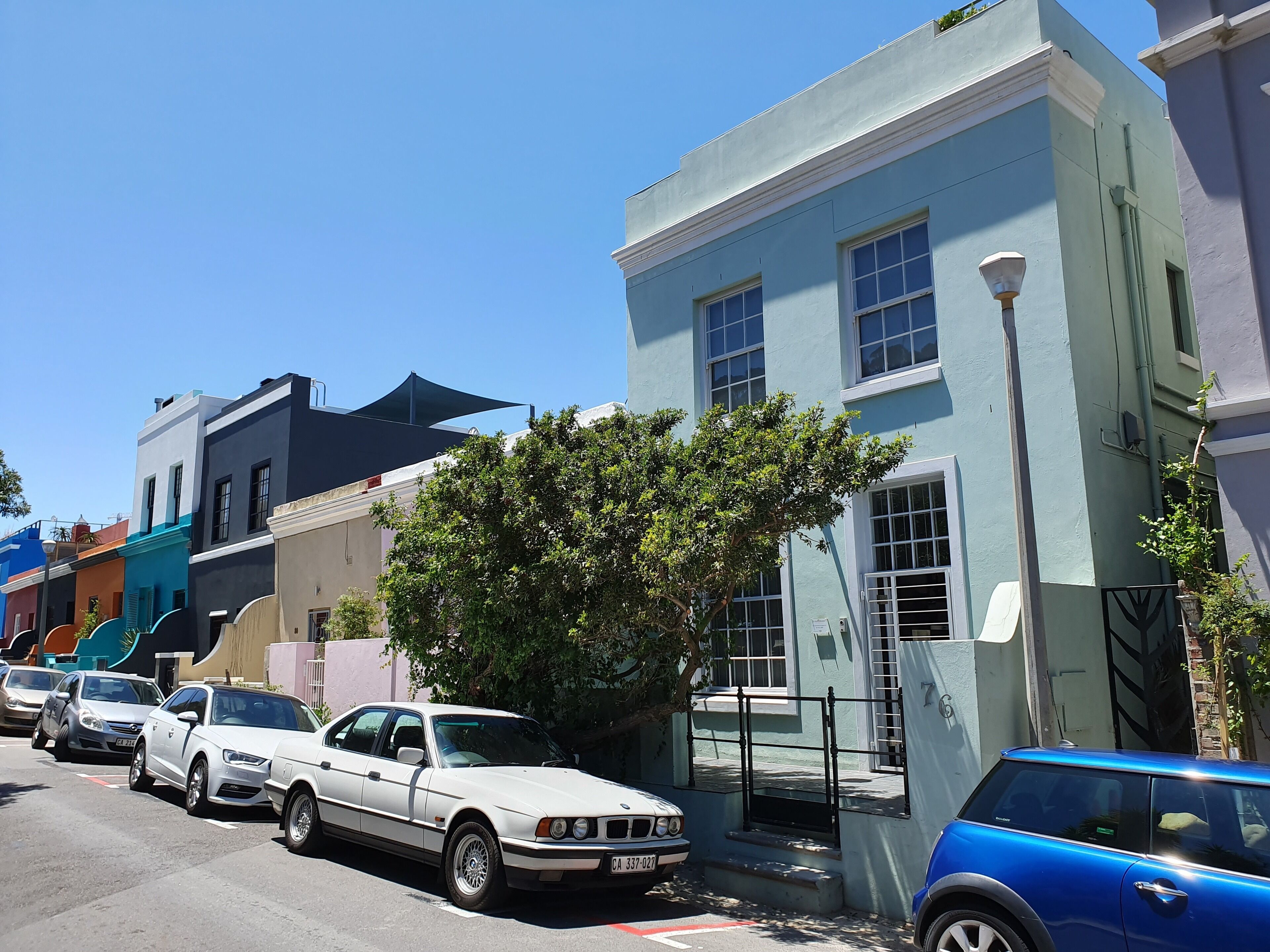 A row of parked cars along a street with colorful buildings.